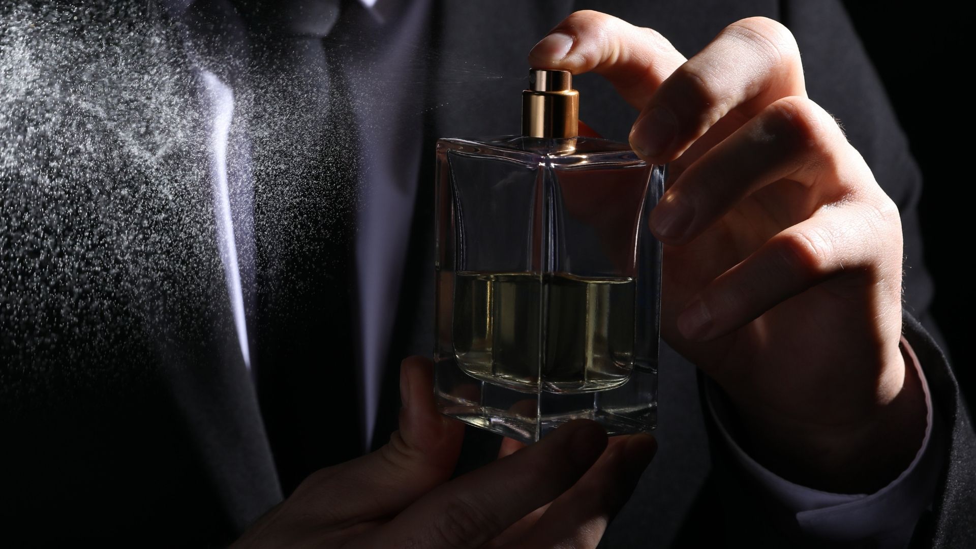 Mężczyzna z flakonem perfum, psikający się